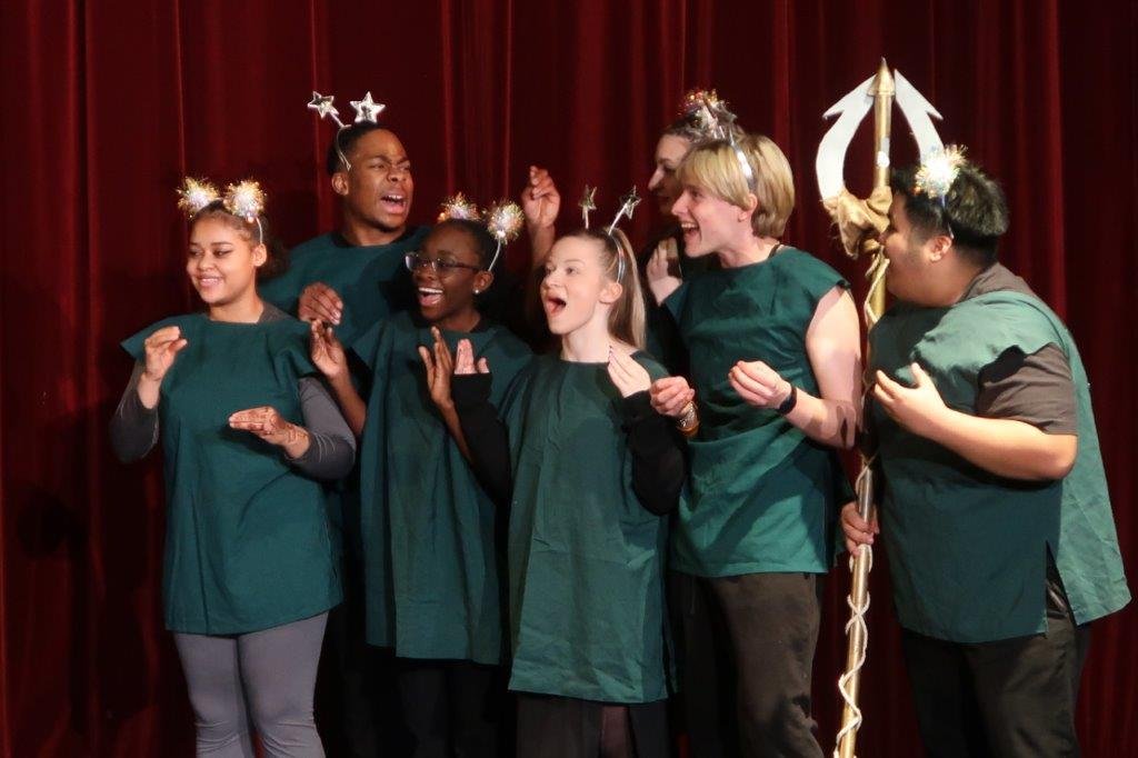  Group of actors dressed in green displaying excitement. 