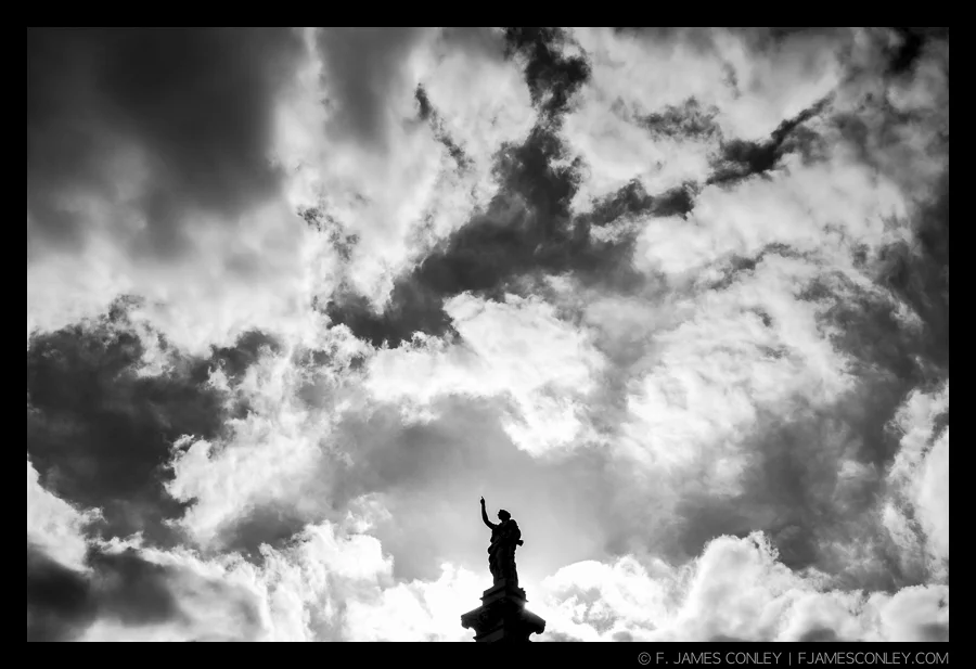 The meaning and symbolism of "clouds" is changed with the context of the subject. The "heavenly" meaning is enhanced because of the subject's pointing finger.
