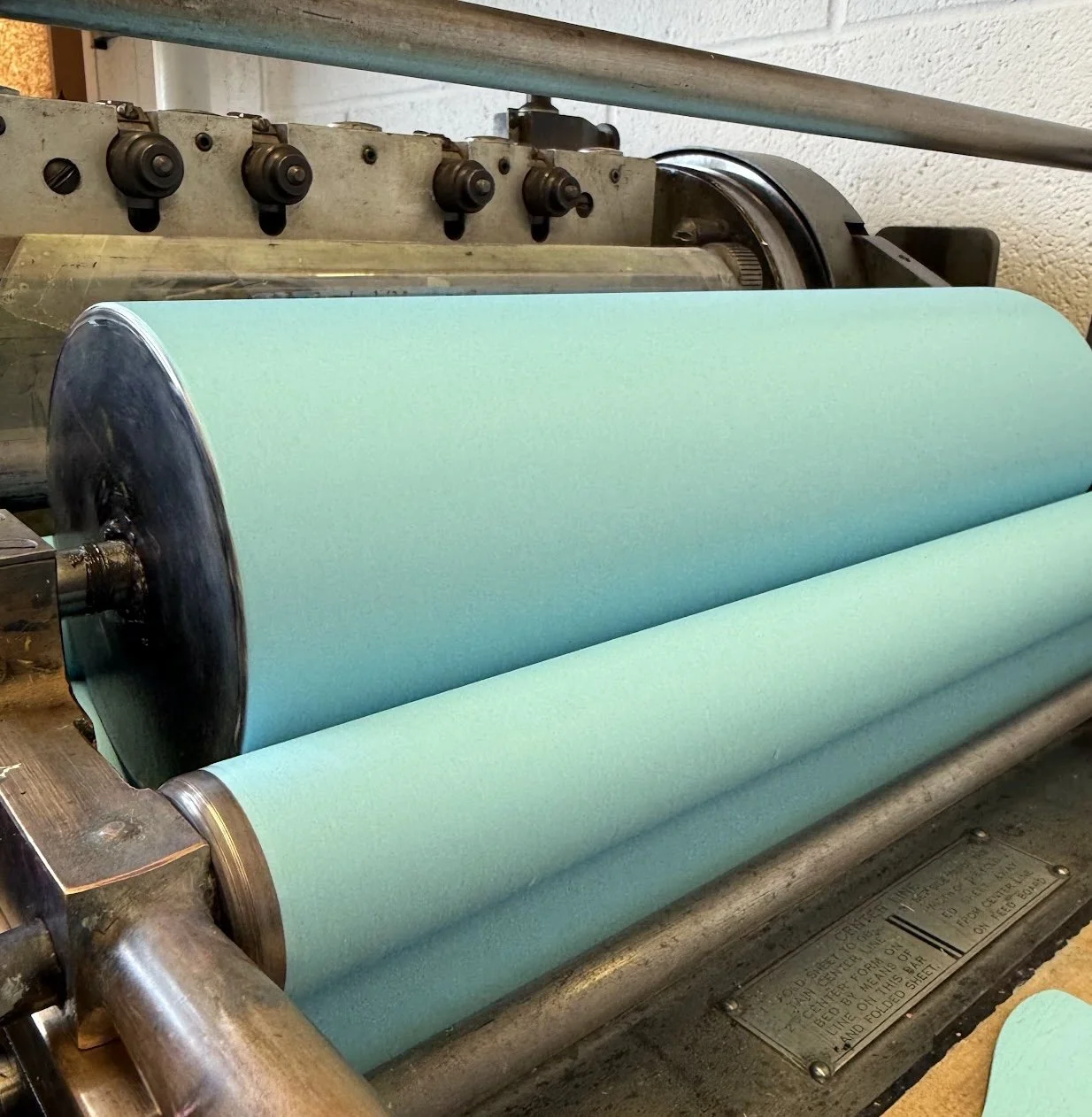 Close-up of inked rollers on a Vandercook No. 4 proof press during relief printing.