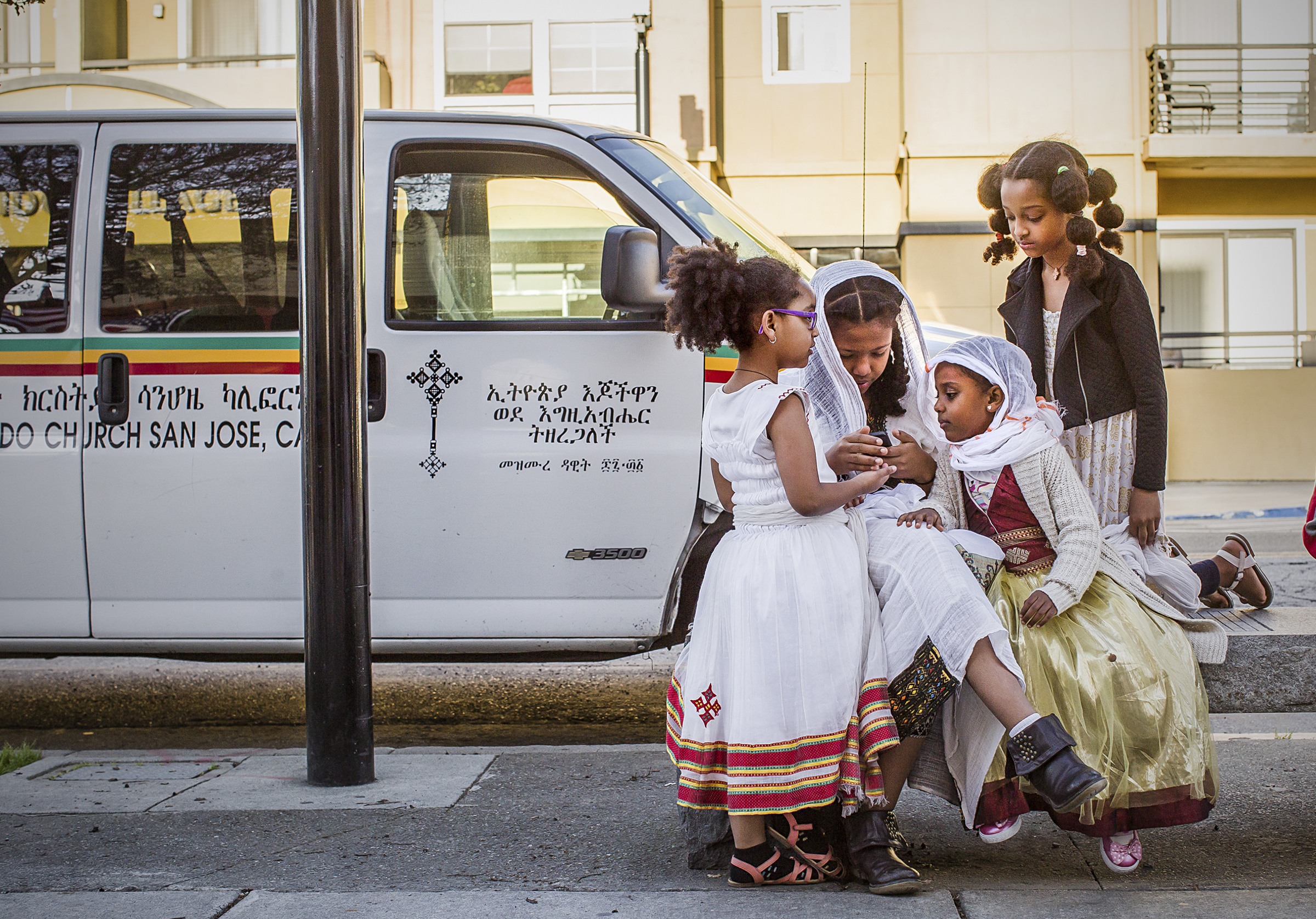  Girls gather outside the Mekane Rama Saint Gabriel Cathedral Ethiopian Orthodox Tewahedo Church in San Jose’s Japantown looking at a cell phone.  
