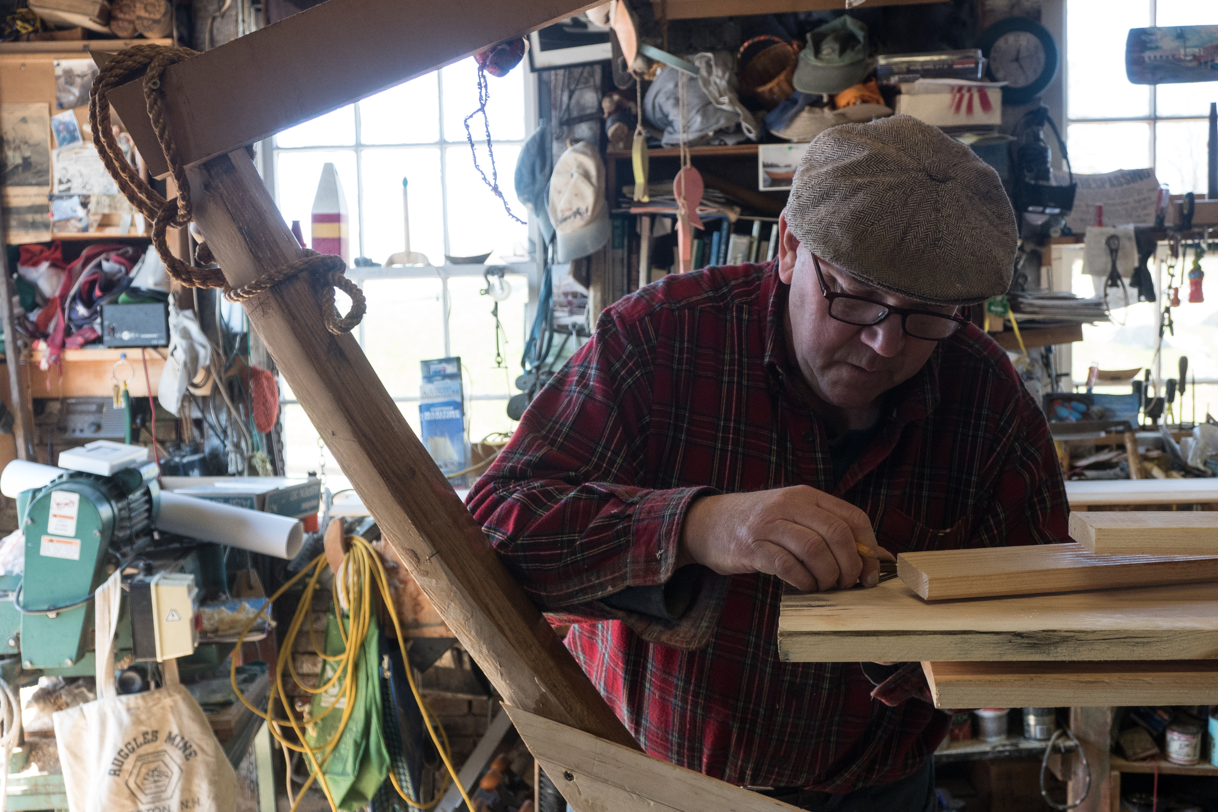Geno measuring a side plank cut for a recreational dory in Gloucester. He mainly works alone during the academic year as the previous running after school program was discontinued due to a lack of interest.