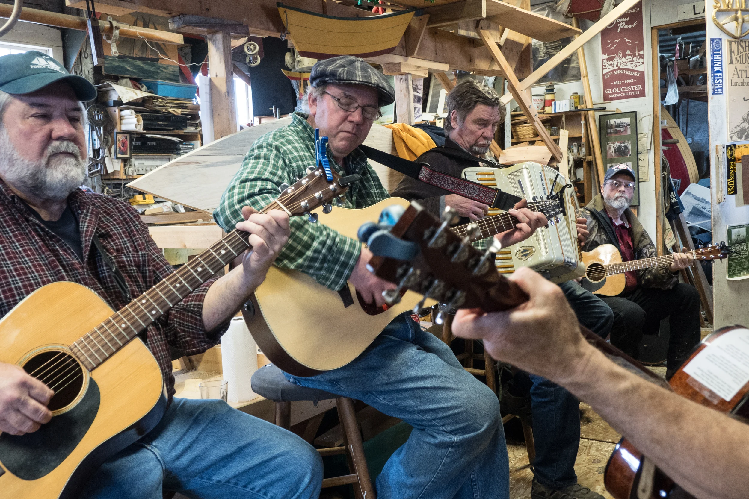   Geno and his friends play folk and sea shanties for a weekly Saturday party in his dory shop. They share fishing stories while looking at old photos and discuss the origins of folk music.  