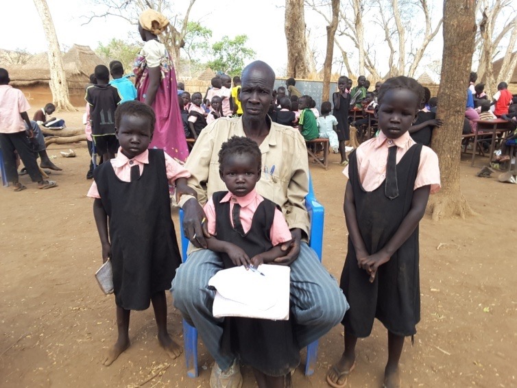 Refugee and now teacher John Yien Pual shown with his children Nyaboth, Nyaduoth, and Nyabhan