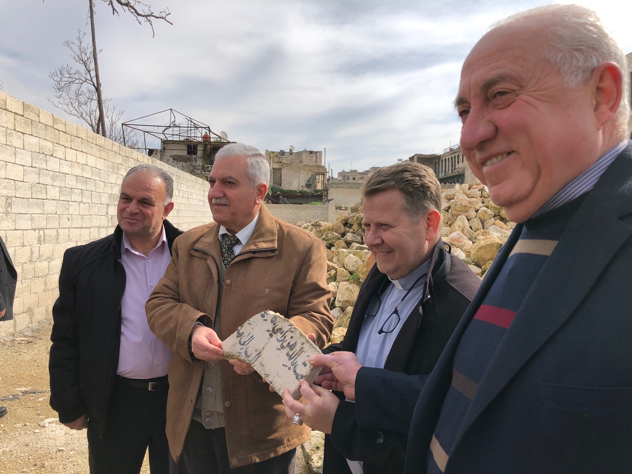  Elder Milad, Elder Feras, Rev. Nseir and Elder Emad holding a piece of the Psalm 23 plaque which used to hang behind the pulpit. It was pulled out of the rubble today and presented to the Outreach team. 