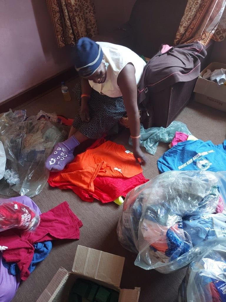 Lucy and Ongai sorting out the shirts and putting them into their sizes of small, medium, large and extra-large and also putting soap and maputi into empty bread packets.