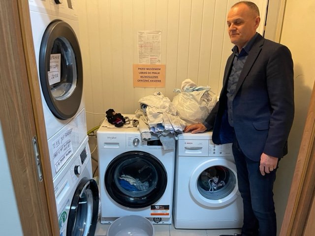   Piotr Nowak standing alongside new washer and dryer machines they were able to purchase for refugee families.  