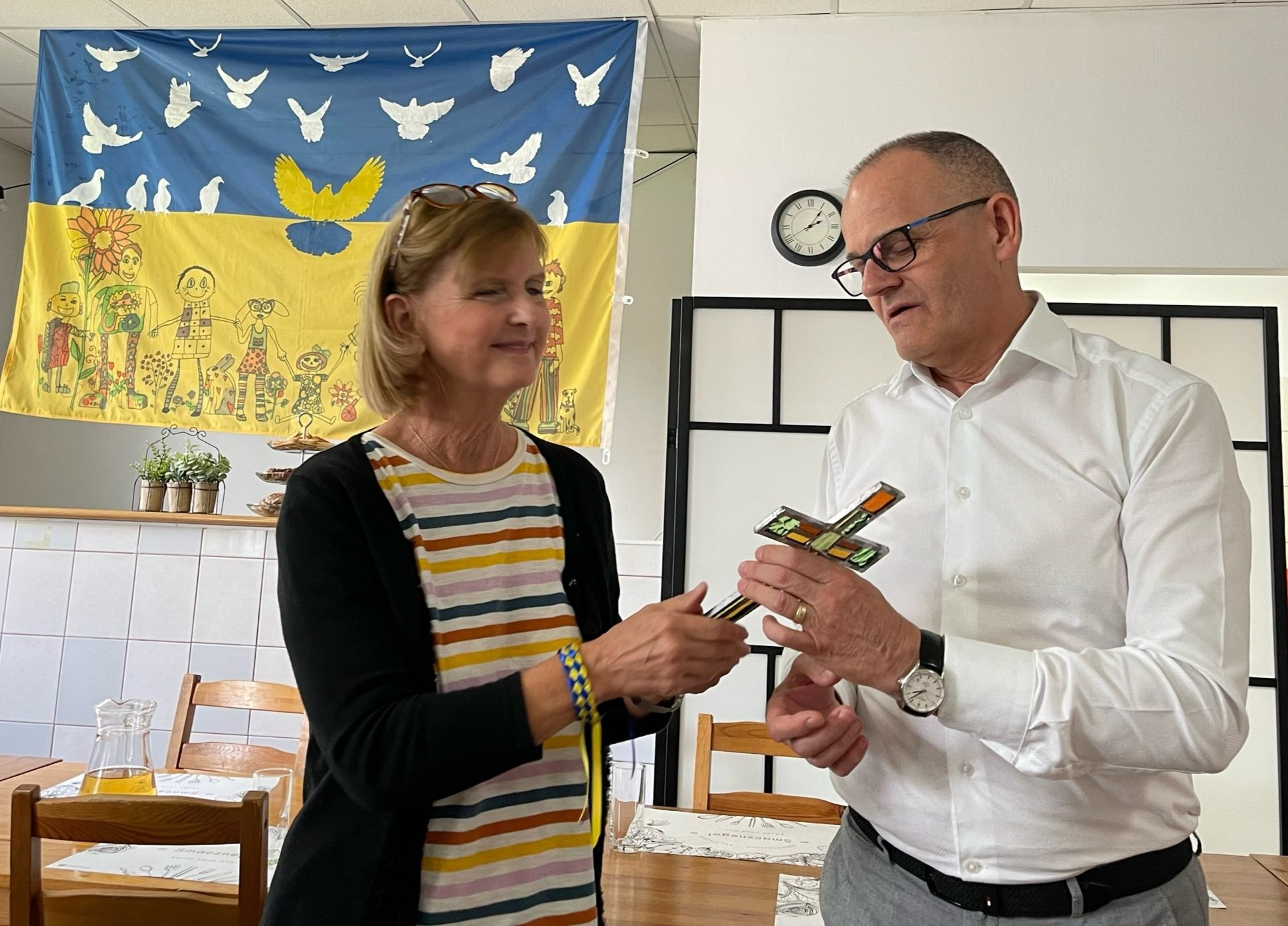   Jill Gilbert of First Presbyterian Columbus presents a glass cross as a gift to Piotr Nowak, president of WSTS. This glass cross was made from stained glass burned in a church and she said, “We remember that from things that were broken and ruined,