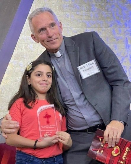   Mark Mueller presents an award for Bible knowledge to one of 12 youth at Aleppo Church  
