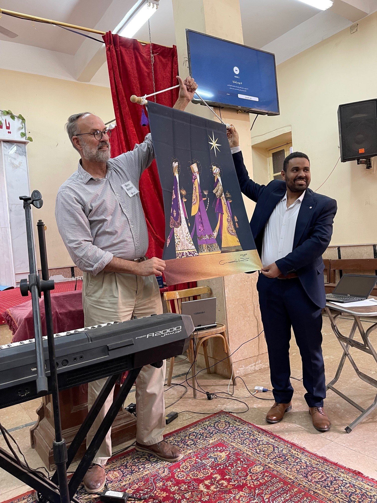 Steve Burgess presents Pastor Rami with a Christmas banner