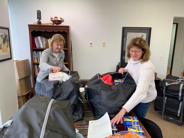 Jill Gilbert and Carol Dublin packing duffel bags in the Franklin office