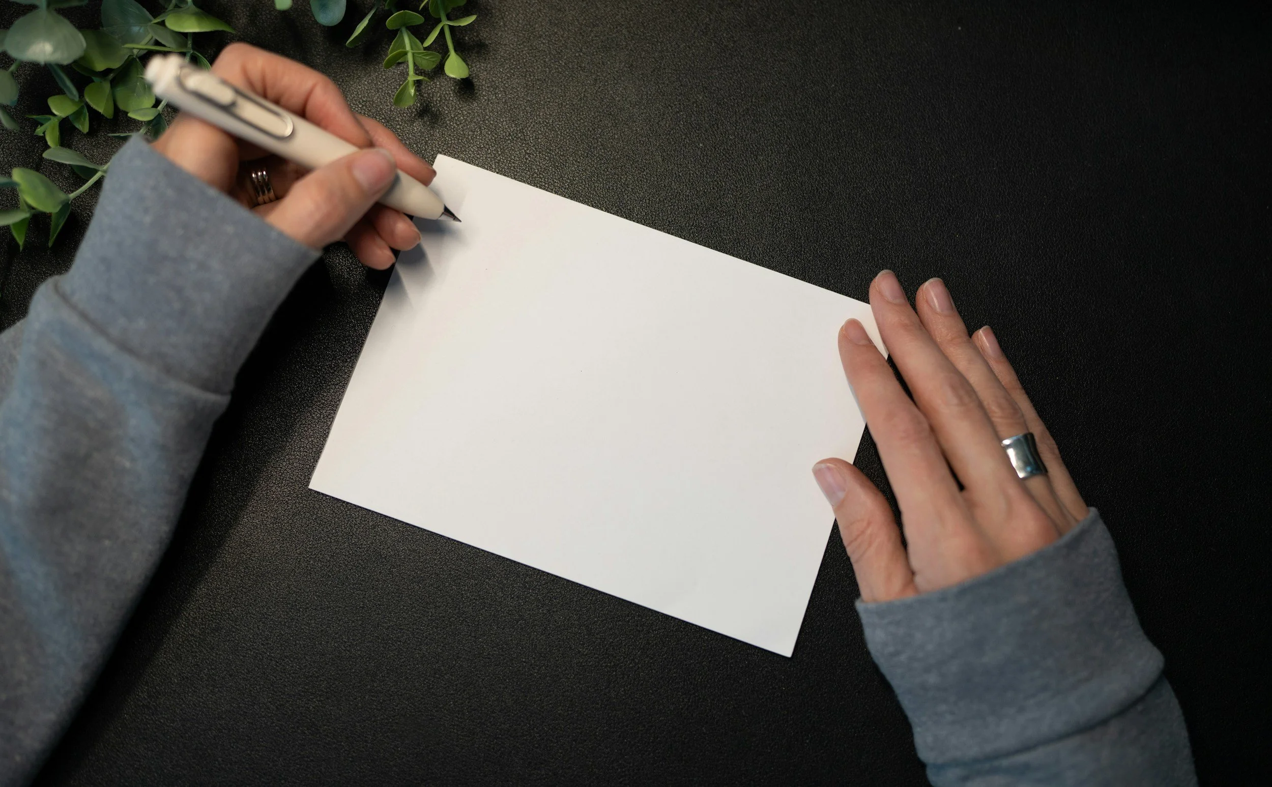 A set of hands writing out a greeting card
