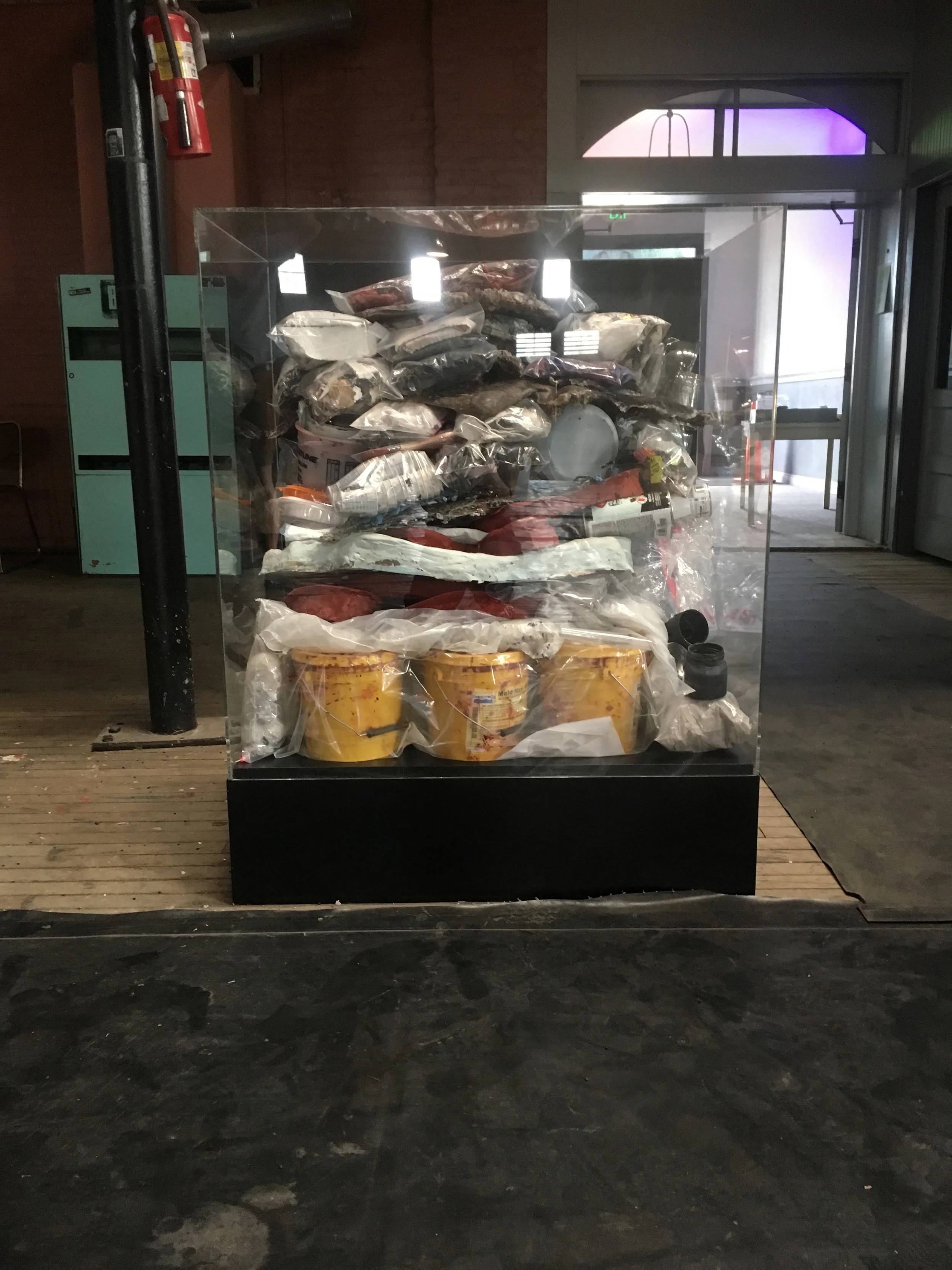  In the same room, towards the exit, was the counterpoint to  Omega.     Alpha  contained every single piece of waste created in the making of Omega. All of it was sorted, bagged, and stacked in a museum vitrine opposite of Omega. The purpose of this