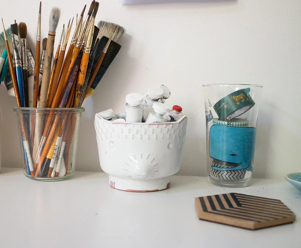 I have a lot of tiny brushes and a few bigger ones - the orange handled ones are my favourites! The little white pot holds my paint tubes and was given as a gift. The whale glass here is perfect for washi tape and is from Anthropologie . 
