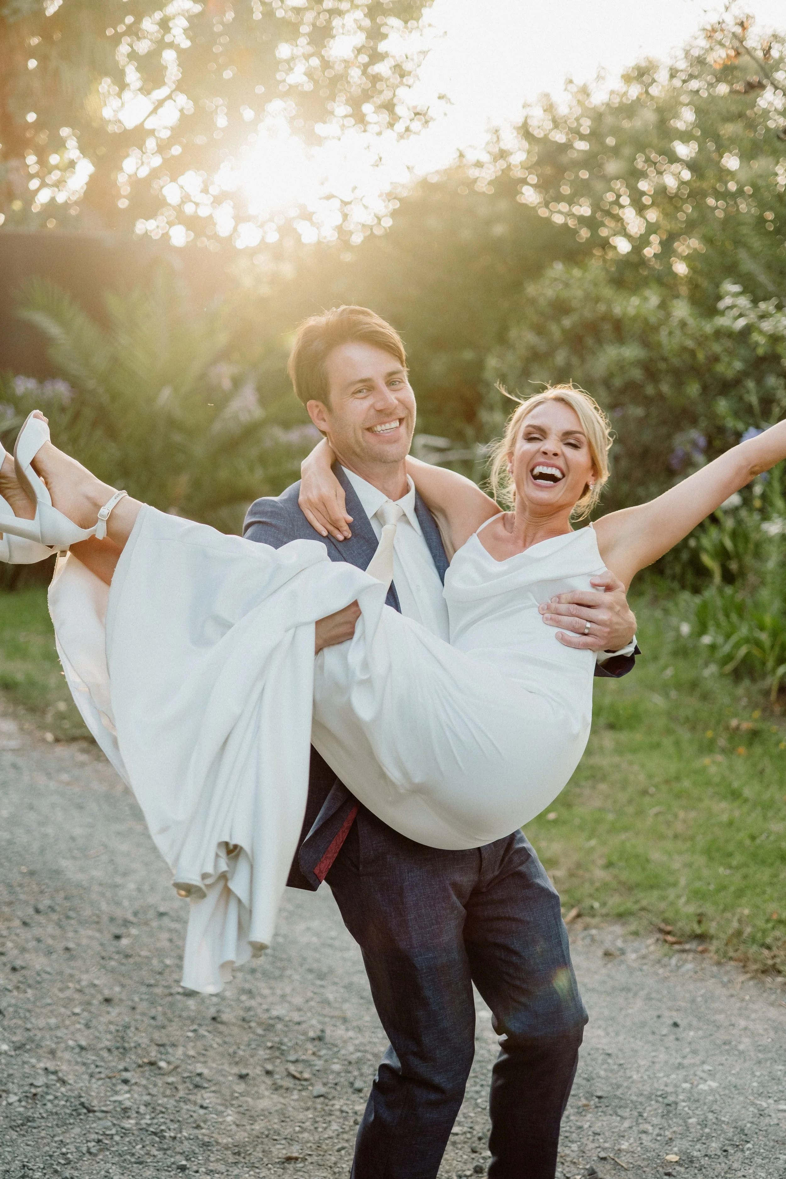 Bride and groom walking through guests throwing flower petals at an outdoor wedding ceremony.