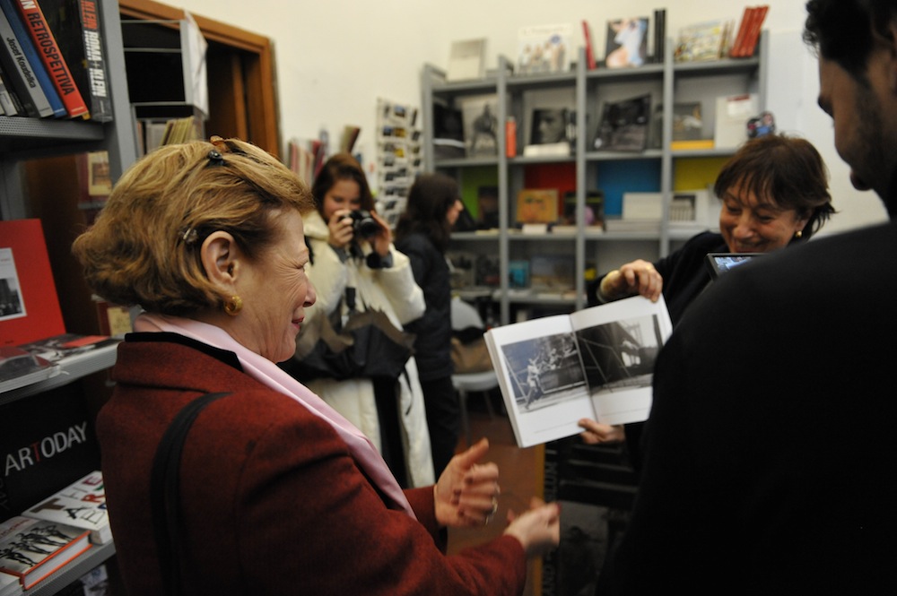 Curator Maria Paola Fornasiero showing exhibition catalog to Nina Rosenblum
