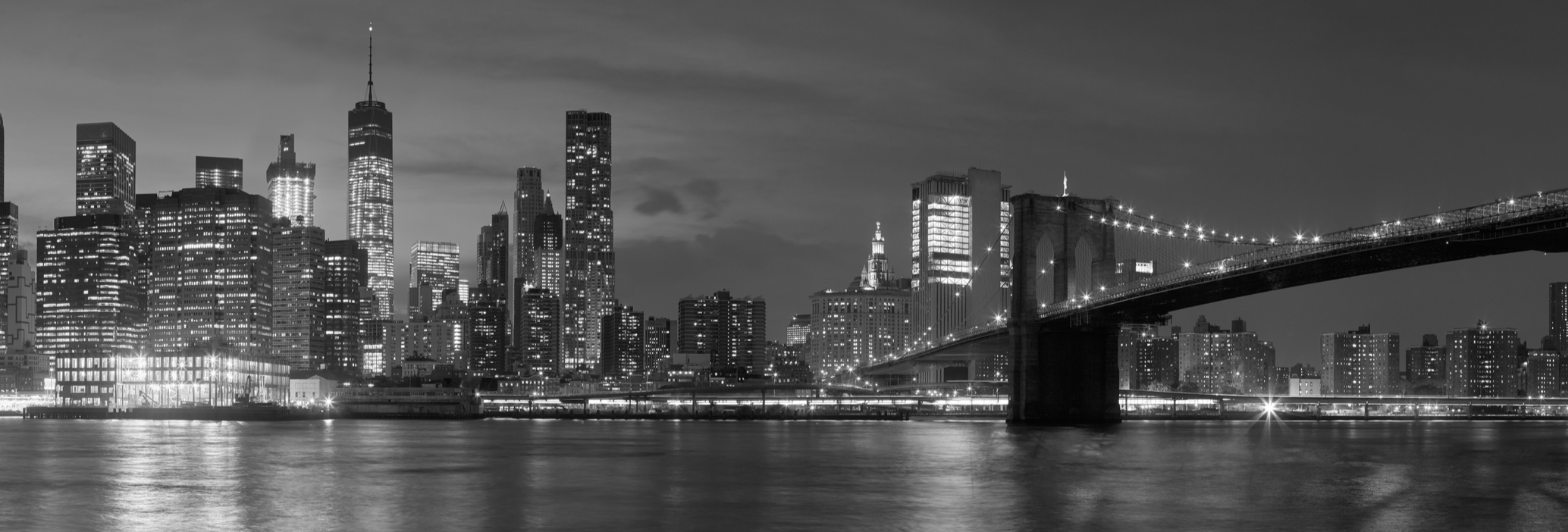 New York city with Brooklyn Bridge, iconic skyline panorama at night in black and white