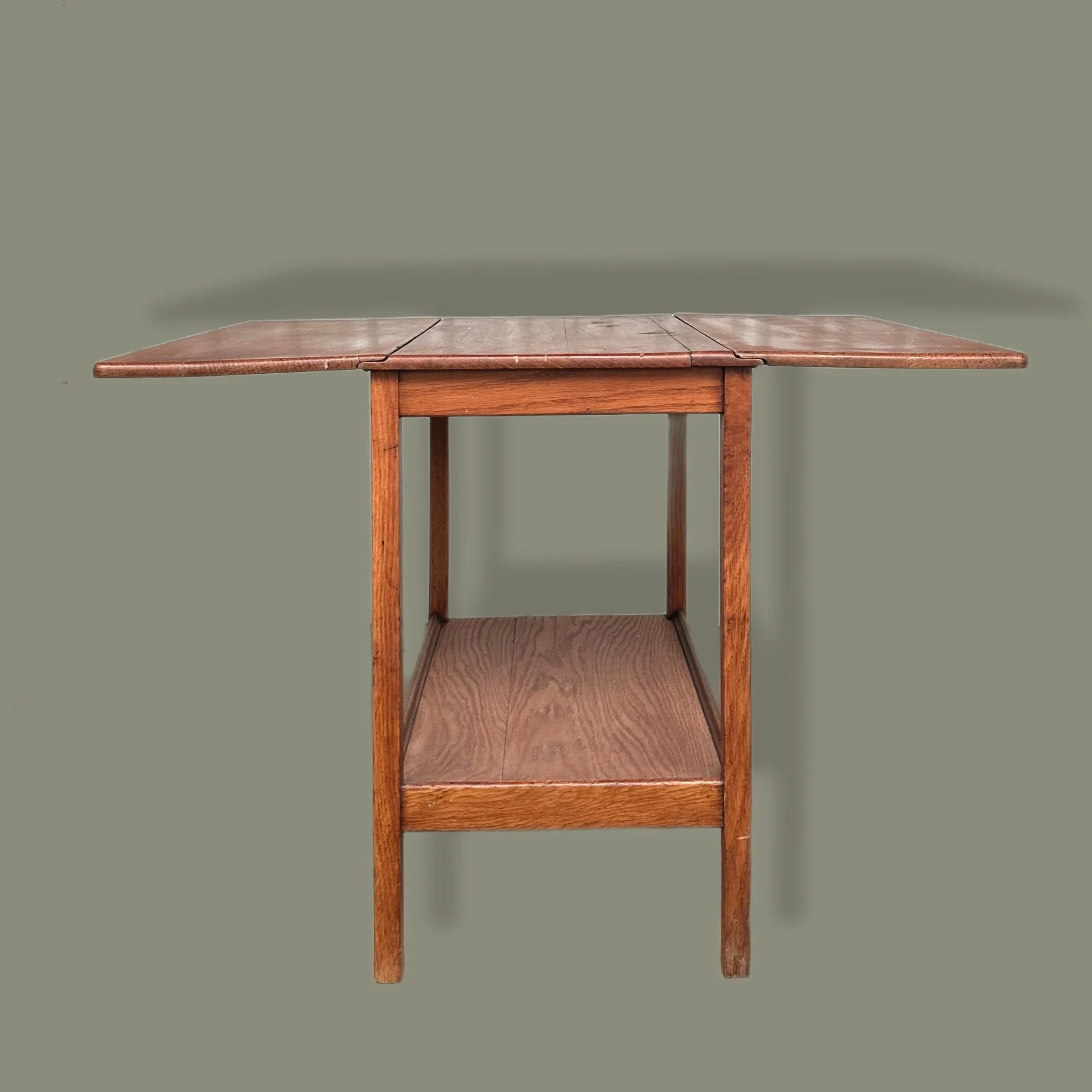  Mesa auxiliar. Inglaterra, años 60. Madera de teca. Con extensiones laterales abatibles tipo mariposa y repisa inferior.  64 x 91 x 61 cm (abierta). 64 x 42.5 x 61 cm (cerrada). 