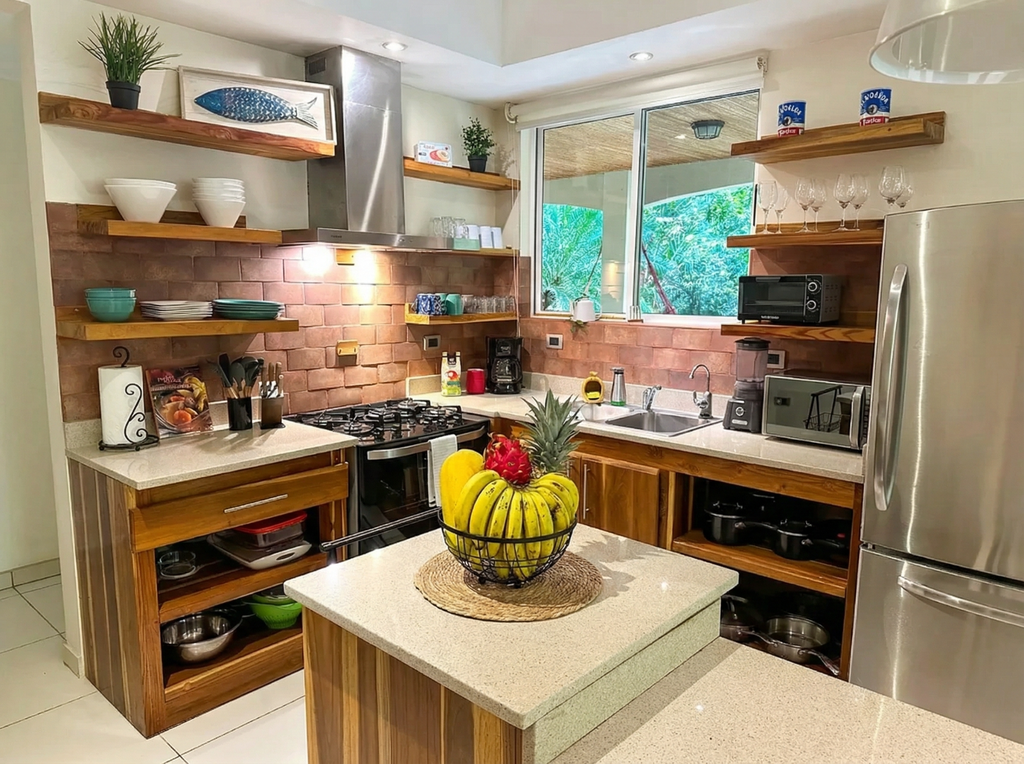 Pacific Suite kitchen in Mal País, Costa Rica with stainless steel appliances, gas stove, open wood shelving, and island with fresh tropical fruit.