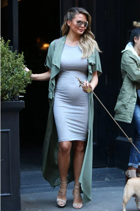 aking pregnancy style cues from Kim Kardashian's maternity uniform , Teigen steps out in a form-fitting gray knit dress layered underneath a floor-length olive jacket. GETTY