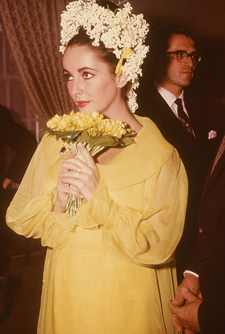 Photo: Getty Images Elizabeth Taylor For her first wedding to longtime love and Cleopatra co-star Richard Burton in March 1964, Taylor went for a mid-'60s mod vibe in a short yellow chiffon frock and floral headdress. She finished off the look with an emerald brooch; one of the many jewels Burton gave her throughout their stormy relationship.