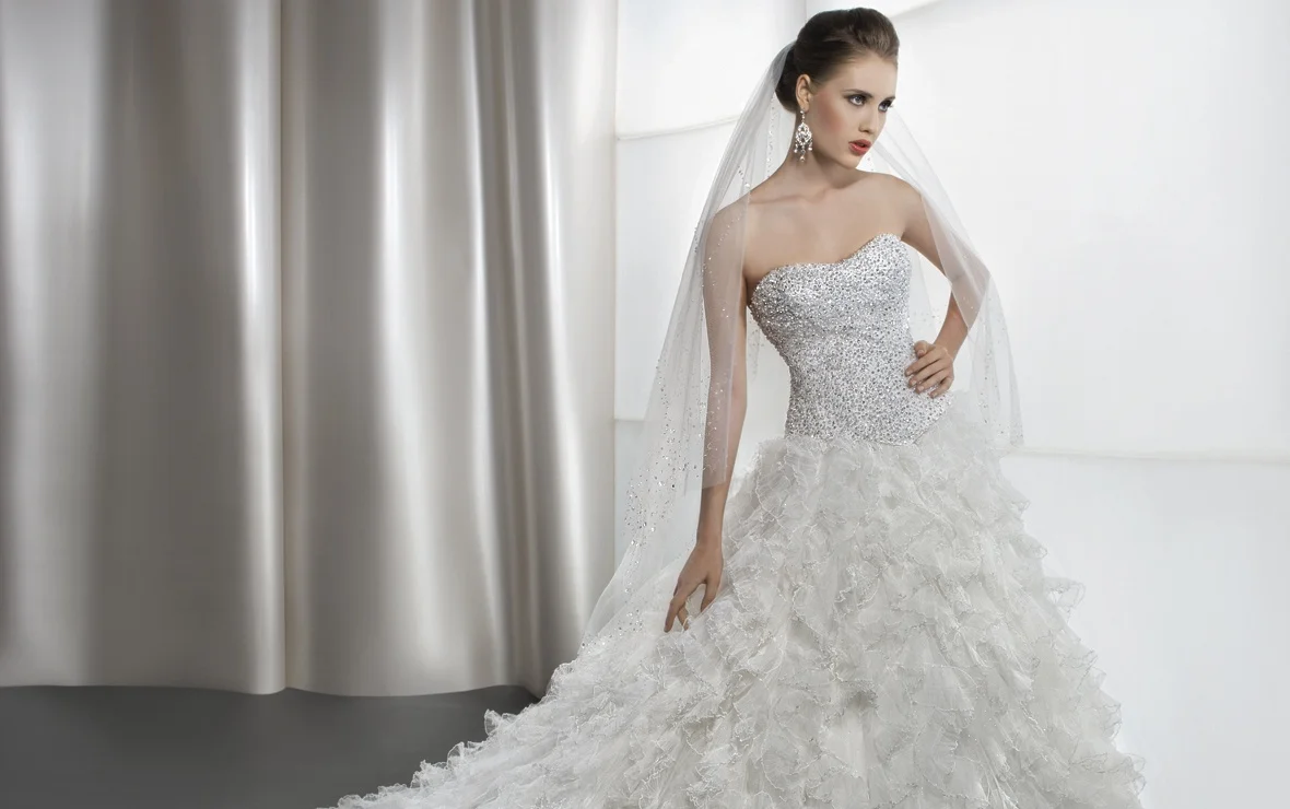 Shimmering, strapless bridal gown with a soft, sweetheart neckline and basque waist. This wedding dress features a full A-line skirt with layers of ruffled, pleated tulle and an attached train. Available Colors: White, Ivory View Size Chart 