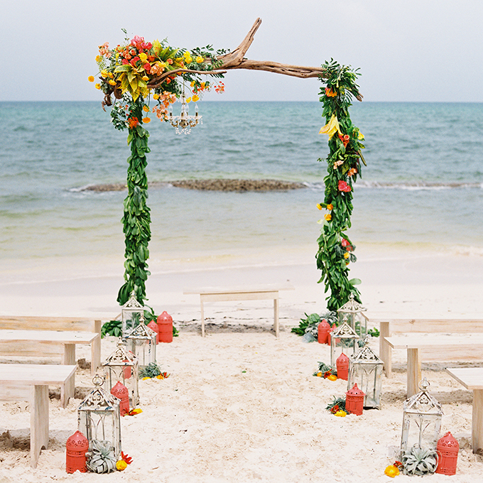 A driftwood arbor is adorned with fresh tropical flowers and greenery for summery, seaside nuptials. Photo: Lane Dittoe