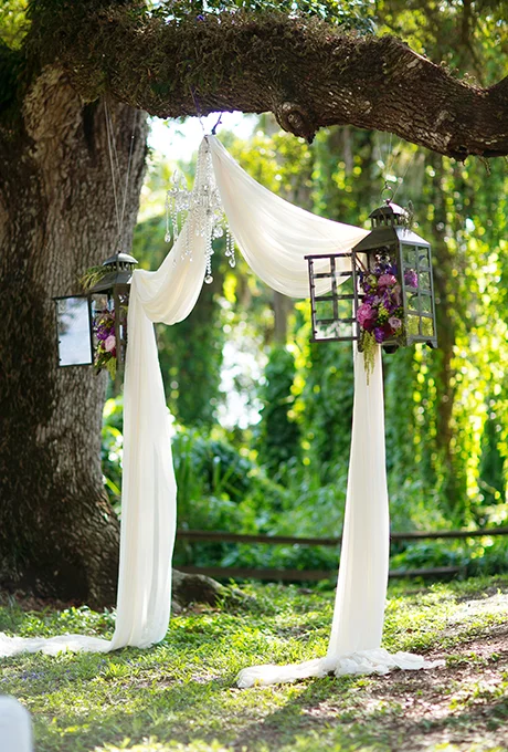 Rustic gets whimsical with this wedding altar consisting of draped fabric, lanterns filled with rich blooms, and a crystal chandelier, all nestled within a tree's sturdy branches. Photo: Stacy Sullivan of Set Free Photography