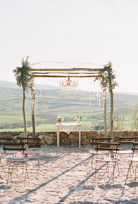 A rustic wooden chuppah, with a scalloped lace canopy and gold and crystal chandelier, overlooks the hills of Tuscany. Photo: Jose Villa