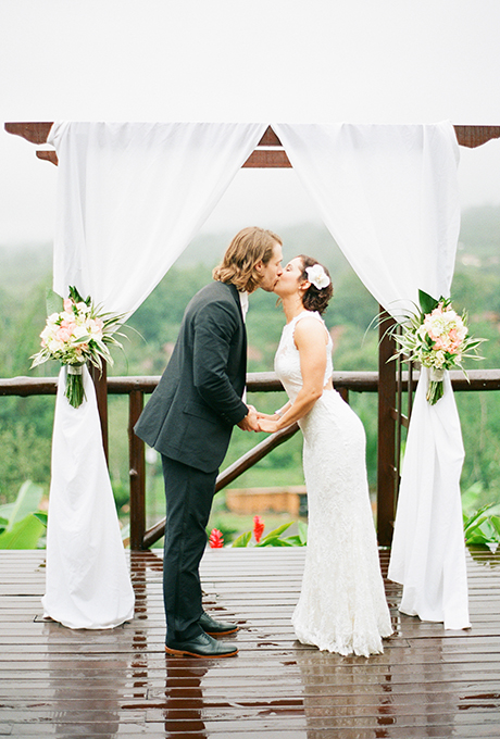 A white curtained wooden arbor, accented with pink and white roses. Photo: Sweet Tea Photography