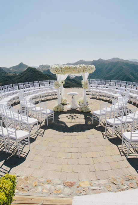 A white chuppah adorned with flowers and airy fabric, created by Luxury Estate Weddings & Events . Photo: Todd Pellowe