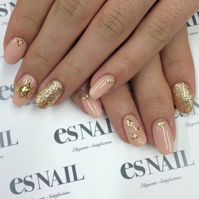 A pink manicure with gold decals and sparkle. Photo: es Nail via Instagram