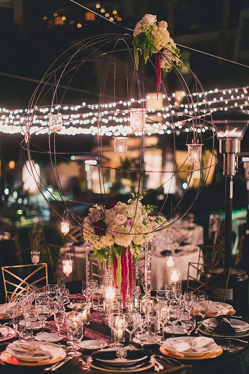 Guests were seated at round tables that were arranged around a checkered dance floor. Each table was decorated with either black or white linens, and topped with a mix of tall, medium, and low arrangements of red and white flowers. "Large metal orbs dripped with flowers and hanging crystals were also suspended from the overhead lighting as unique centerpieces," Remy says.