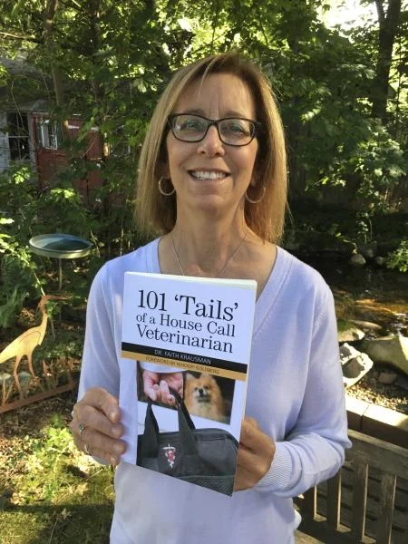 Dr. Krausman holding her book, 101 ‘Tails’ of a House Call Veterinarian