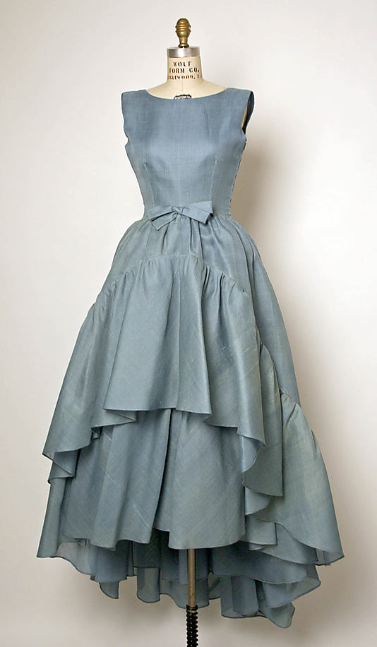 House of Balenciaga, Circa 1960. Note the high/low cut of the skirt and the simple bowed sash at the waist. Perfect Adornment.