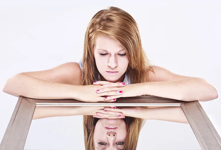 bigstock_Young_Woman_Looking_Into_A_Mir_5503859.jpg