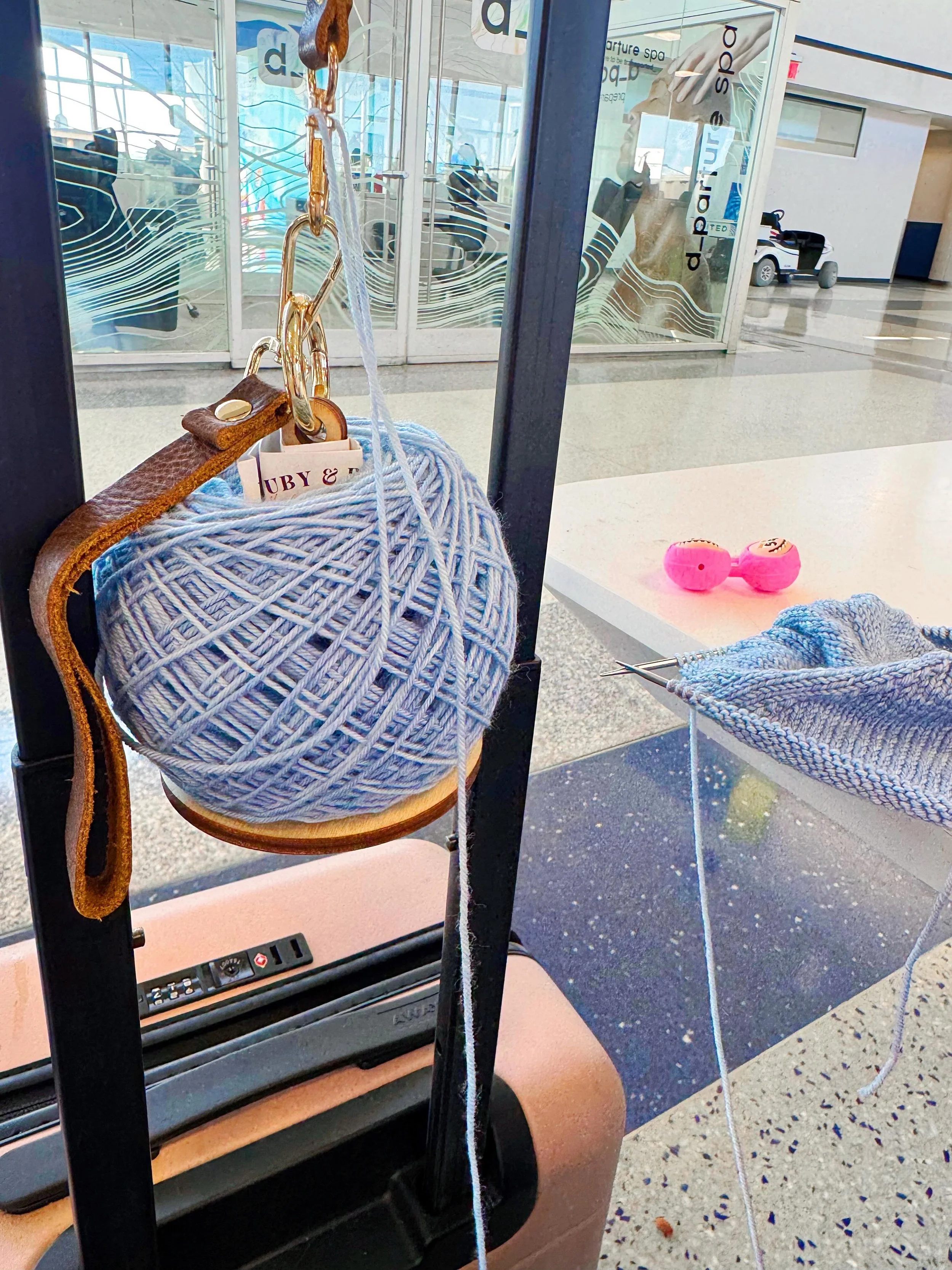 On the road again! Heading back to Austin, TX, for work (or what&rsquo;s left of it). No time like the present to whip out my @lemonwood.love yarn minder and my new Musselburgh for Scott featuring @ruby_and_roses_yarn&rsquo;s Great Lakes colorway ✈️ 