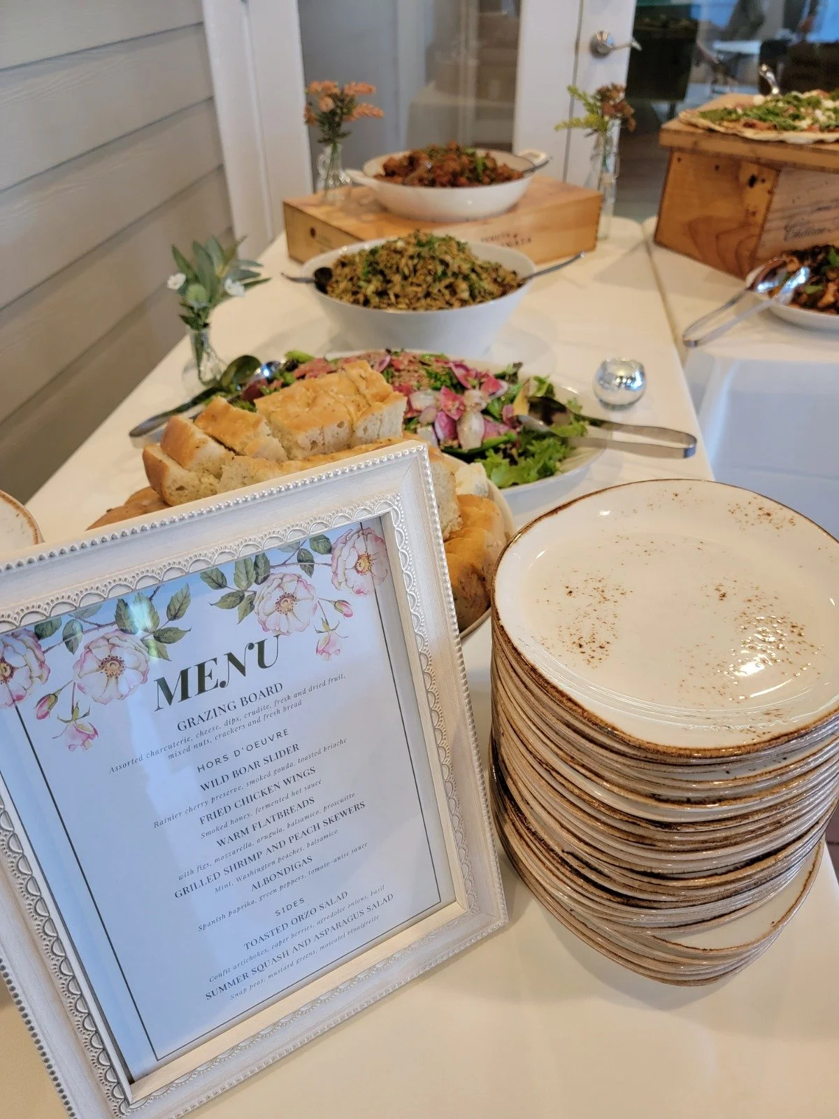 An elegant, fully-plated wedding buffet table featuring a detailed menu card describing each delicious dish and entree.