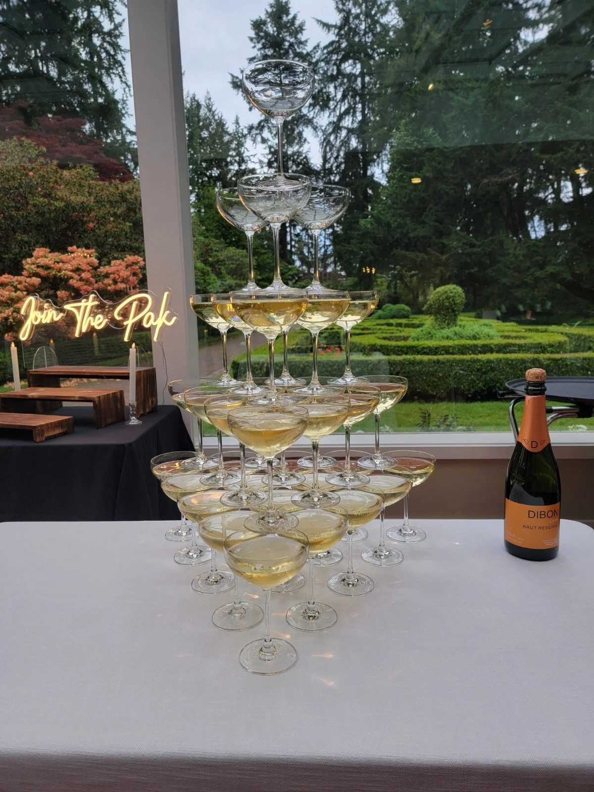 A beautiful and classic tower of champagne glasses set up for a celebration in an elegant wedding reception setting.