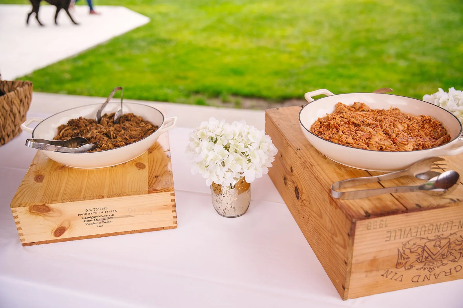 Delicious buffet dishes beautifully served on a creative, rustic display built from wooden wine boxes, centered with a vase of white flowers.