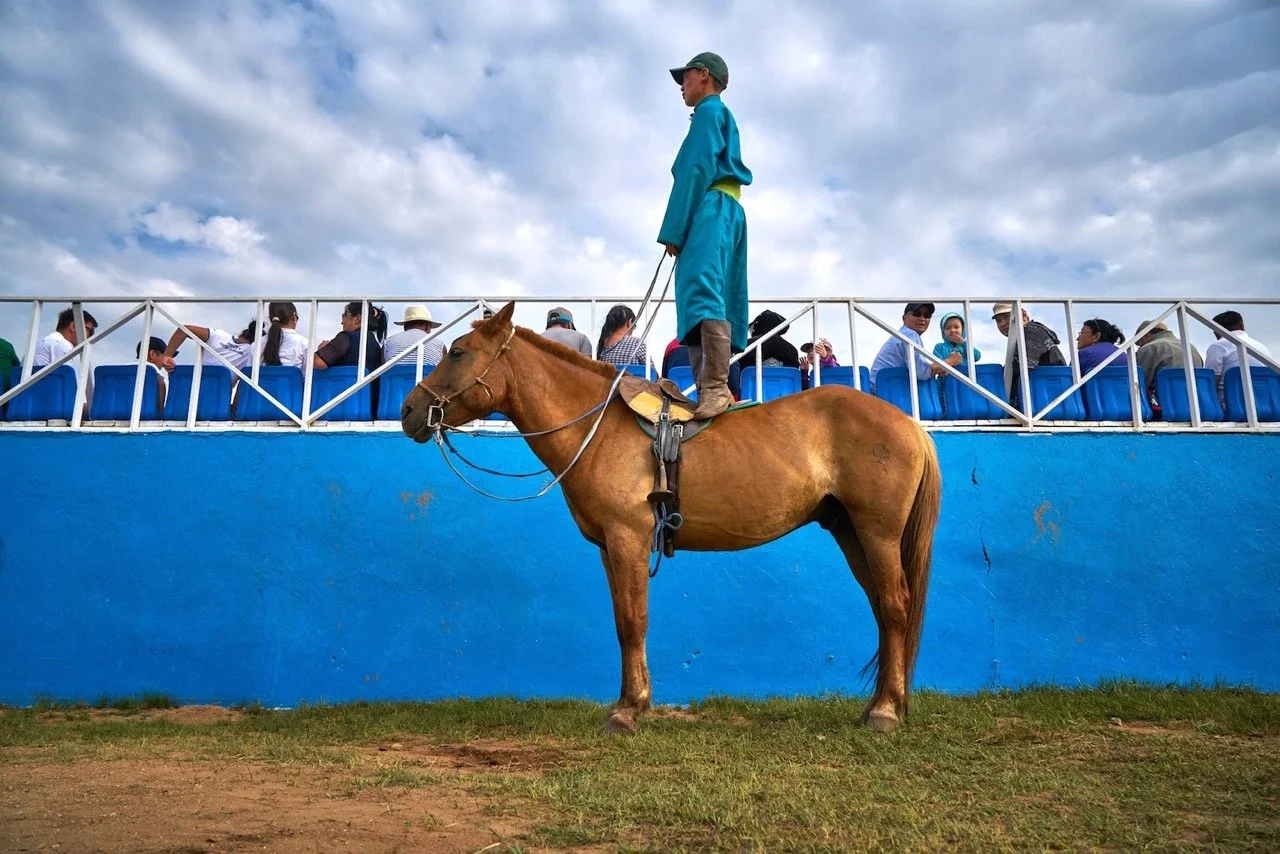 A person on a horse watching horse at the Naadam Festival in Mongolia. Film Mongolia. Filming in Mongolia. Producer in Mongolia. Film Production Service in Mongolia. Fixer Service Mongolia.