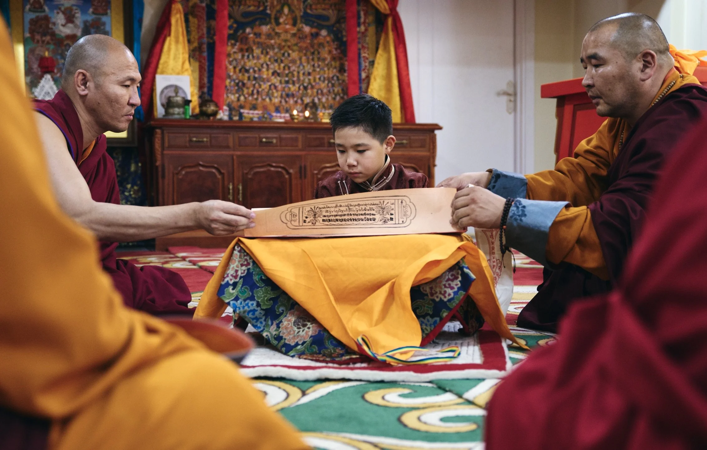 Monks and a young Bogd boy reading Tibetan script during a ceremony in a temple. Film Mongolia. Filming in Mongolia. Producer in Mongolia. Film Production Service in Mongolia. Fixer Service Mongolia.