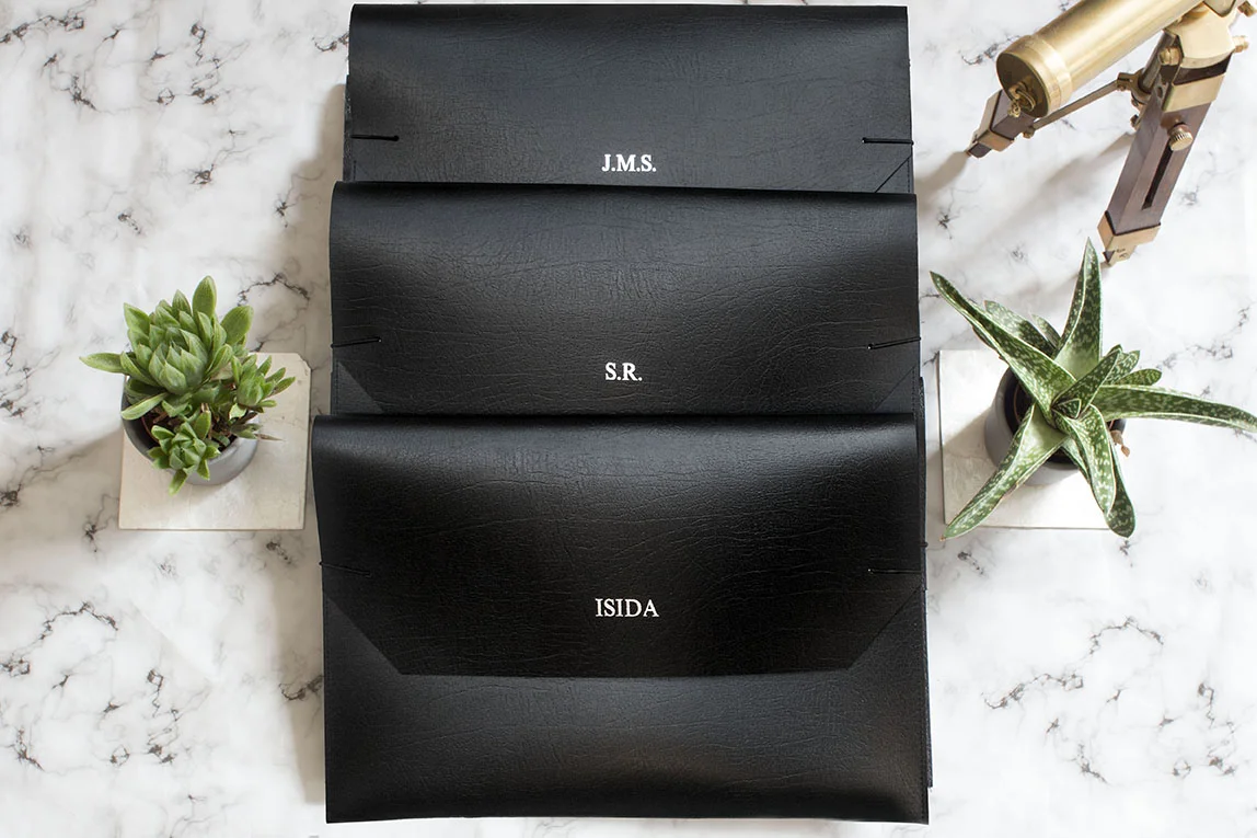 3 leather laptop sleeves with personalised foil embossed name and initials on a marble background