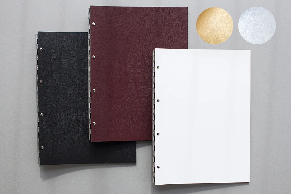 black, red and white leather portfolios with staineless steel hinges to bind your work on a grey background