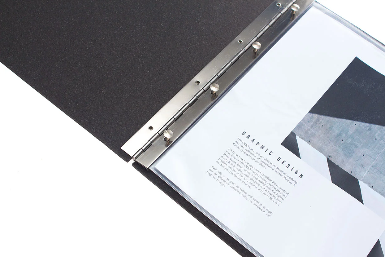 open view of a graphic design black leather A3 landscape portfolio folder, showing the stainless steel hinges and screw-post with an open page of graphic design work