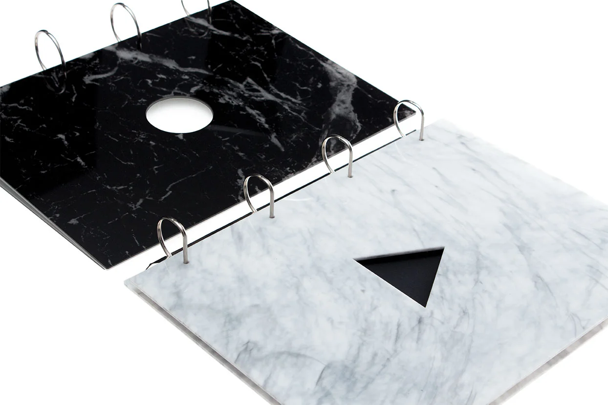 Two portfolios made of marble effect acrylic perspex with geometric shapes laser cut out of the centre of the front cover to show a customers name