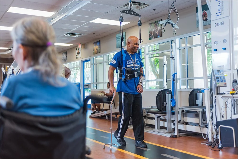 Patient walking during rehabilitation therapy session using support harness in clinic