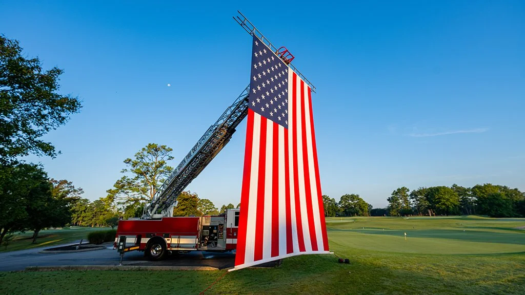 Bowling Green Fire Department ladder truck displaying a giant American flag at the Pars With Patriots Invitational.