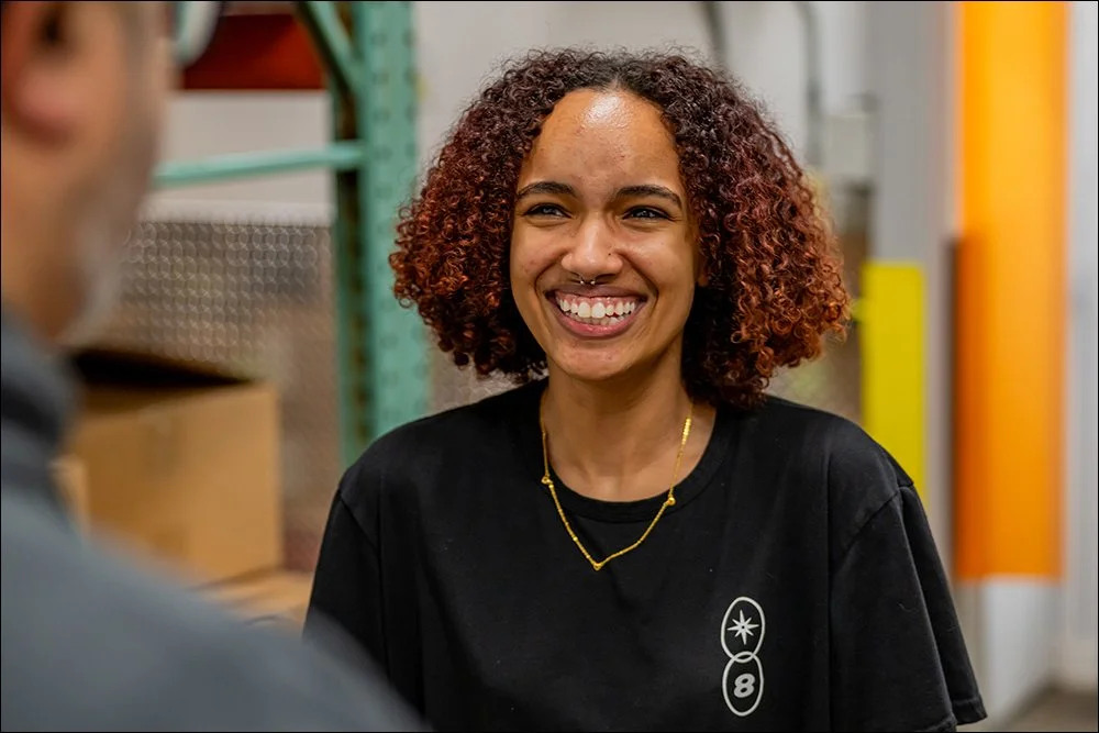 Smiling employee portrait in warehouse environment with shelving and equipment in background