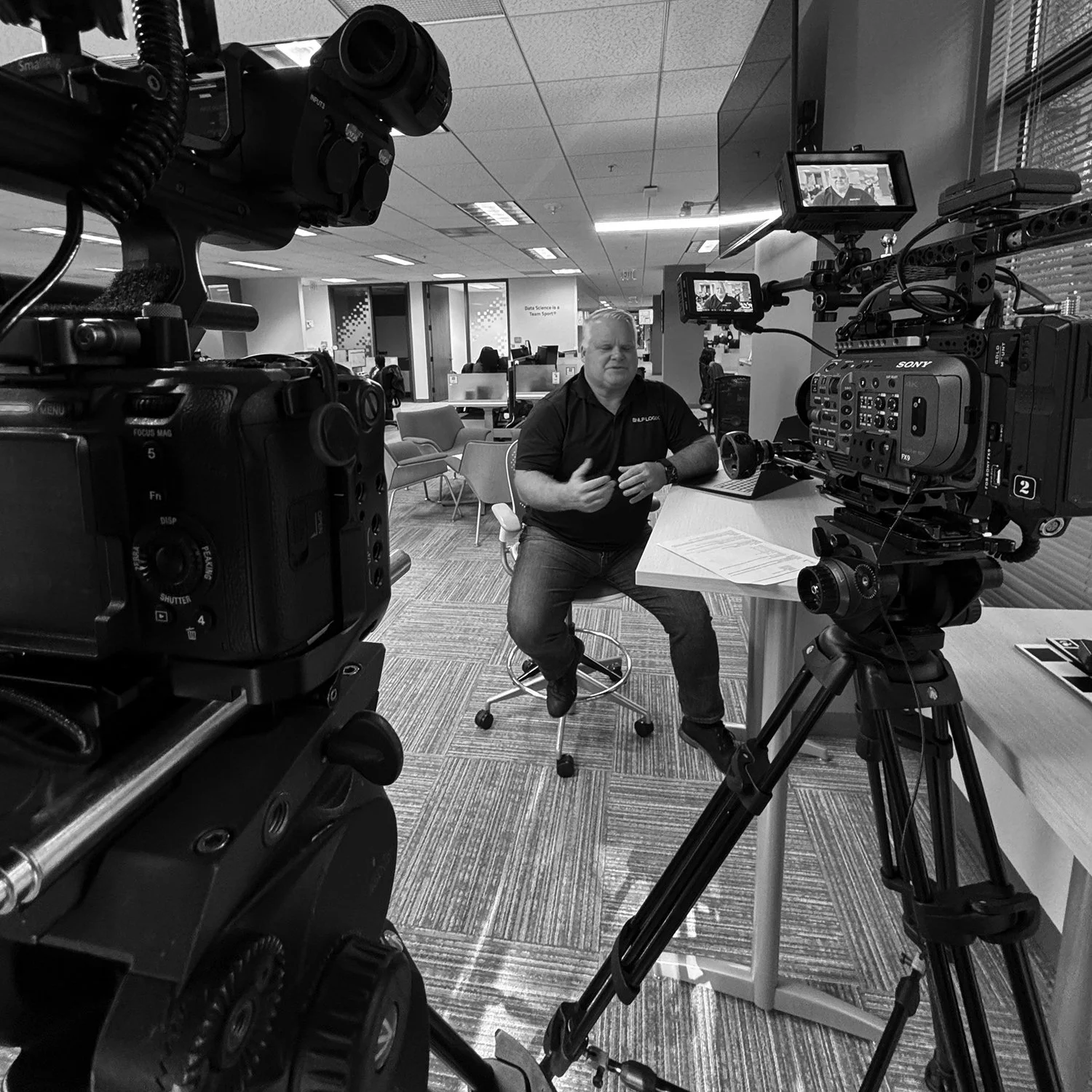 Corporate interview video production setup in office environment with multiple cameras and lighting