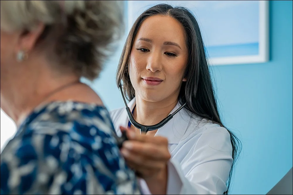 Nurse using stethoscope to check patient vitals during exam in clinic setting